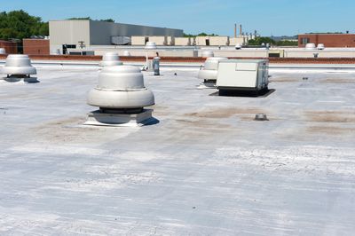 Flat rooftop with ventilation units and HVAC equipment under a clear sky.