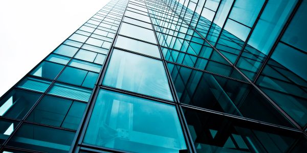Looking up at a modern glass skyscraper reflecting the sky.