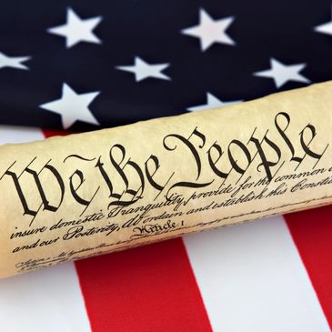 Scroll of the U.S. Constitution on an American flag background.