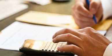 Person using a calculator and writing on paper at a desk.
