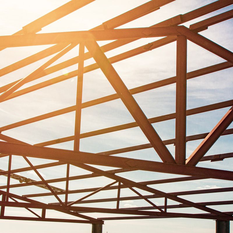 installation of hangar metal structures using a crane and installers, against the background of a blue sky