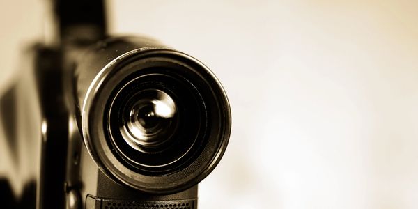 Close-up of a camera lens with a soft sepia tone.