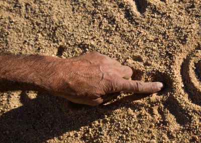 Hand drawing circles in sand.