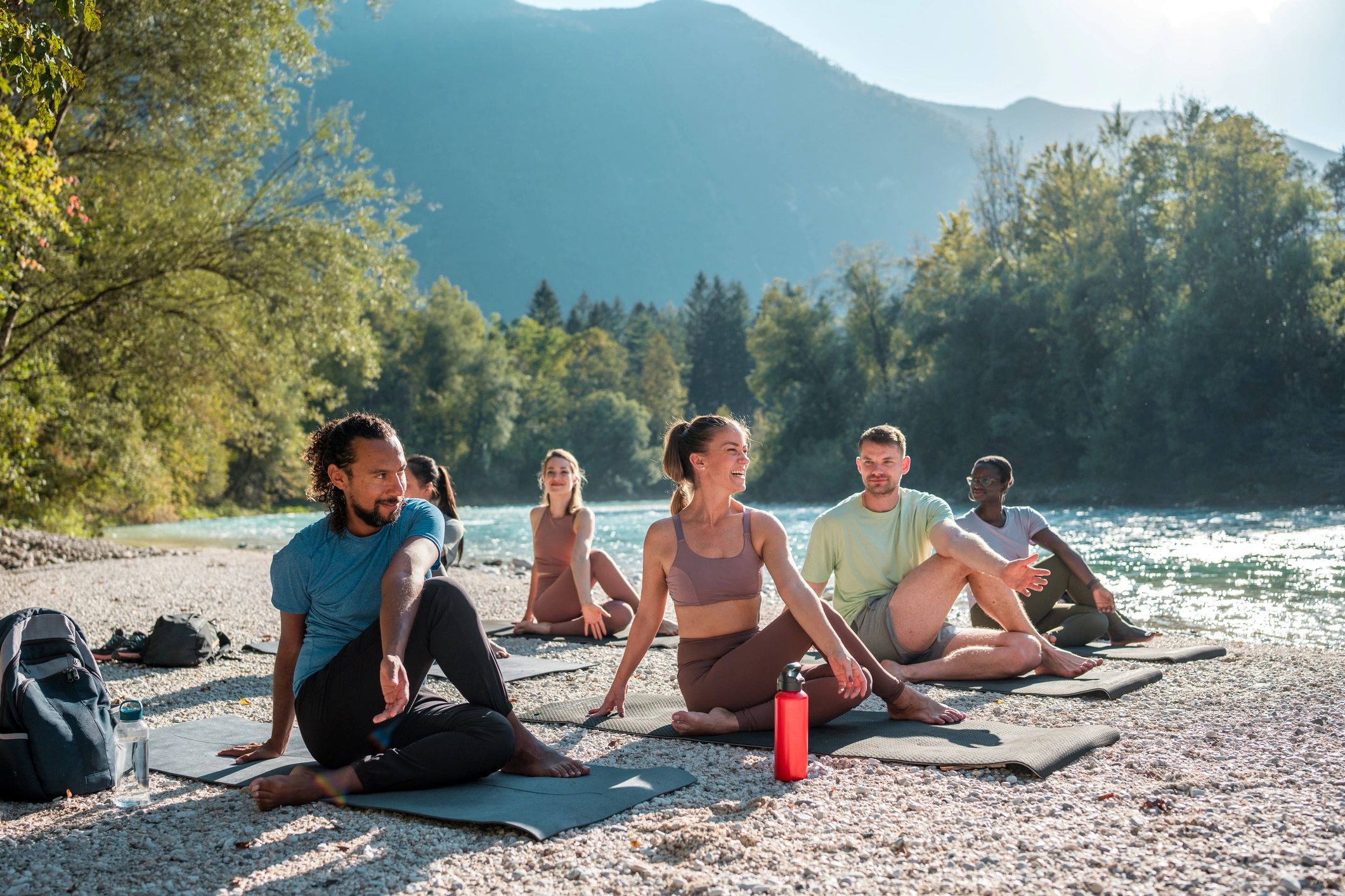 Group doing yoga outdoors by a river.