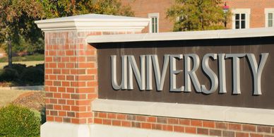 A brick and stone university sign outdoors.
