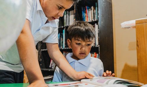 Two boys reading a book together.