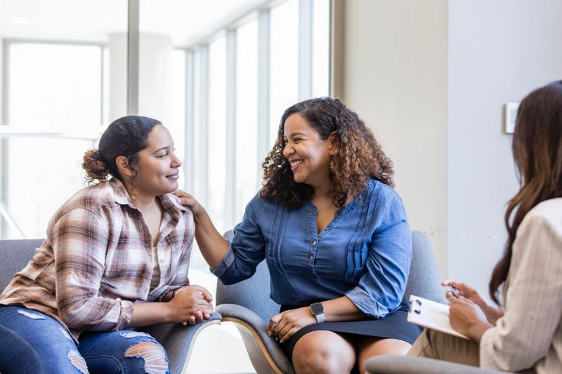 After telling the therapist how much she loves her daughter, the mother puts her hand on her shoulder and smiles proudly.