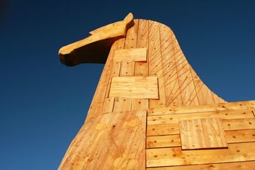 Wooden horse sculpture against a clear blue sky.