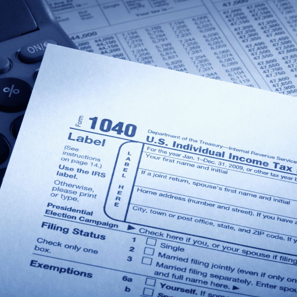 Close-up of a U.S. Individual Income Tax Form 1040 with a calculator and financial data.