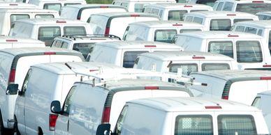 A large fleet of white cargo vans parked closely together.