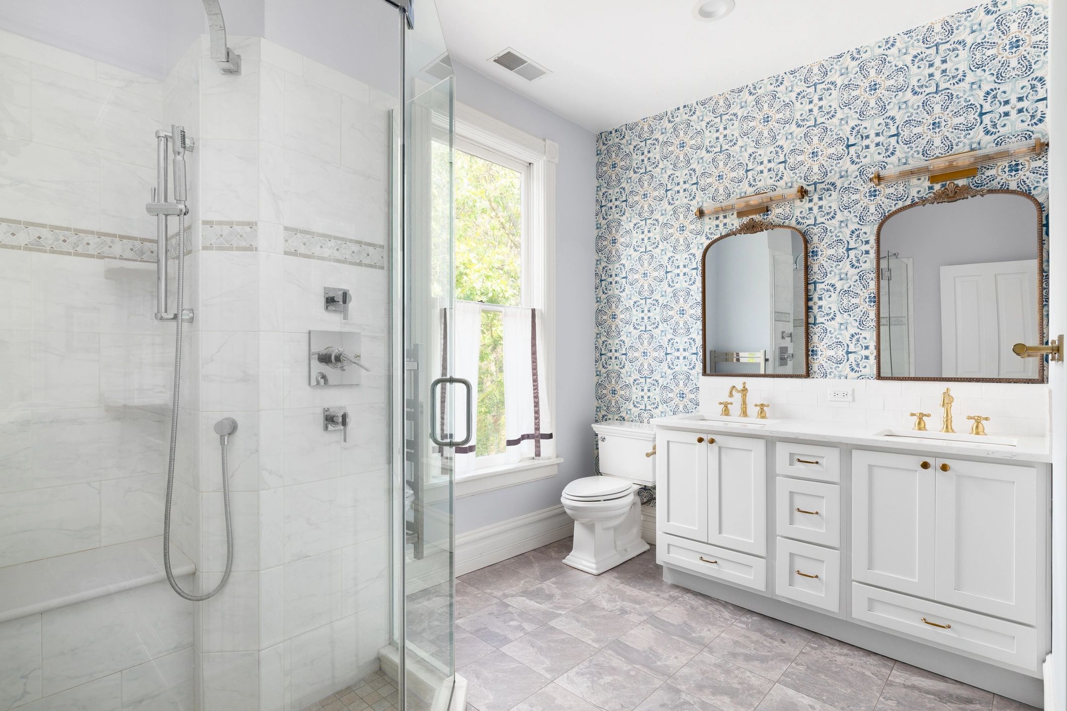 Bright bathroom with patterned wallpaper and glass shower.