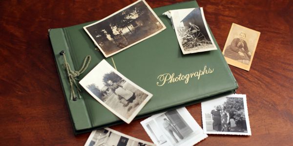 Vintage photo album with black-and-white photos scattered around.