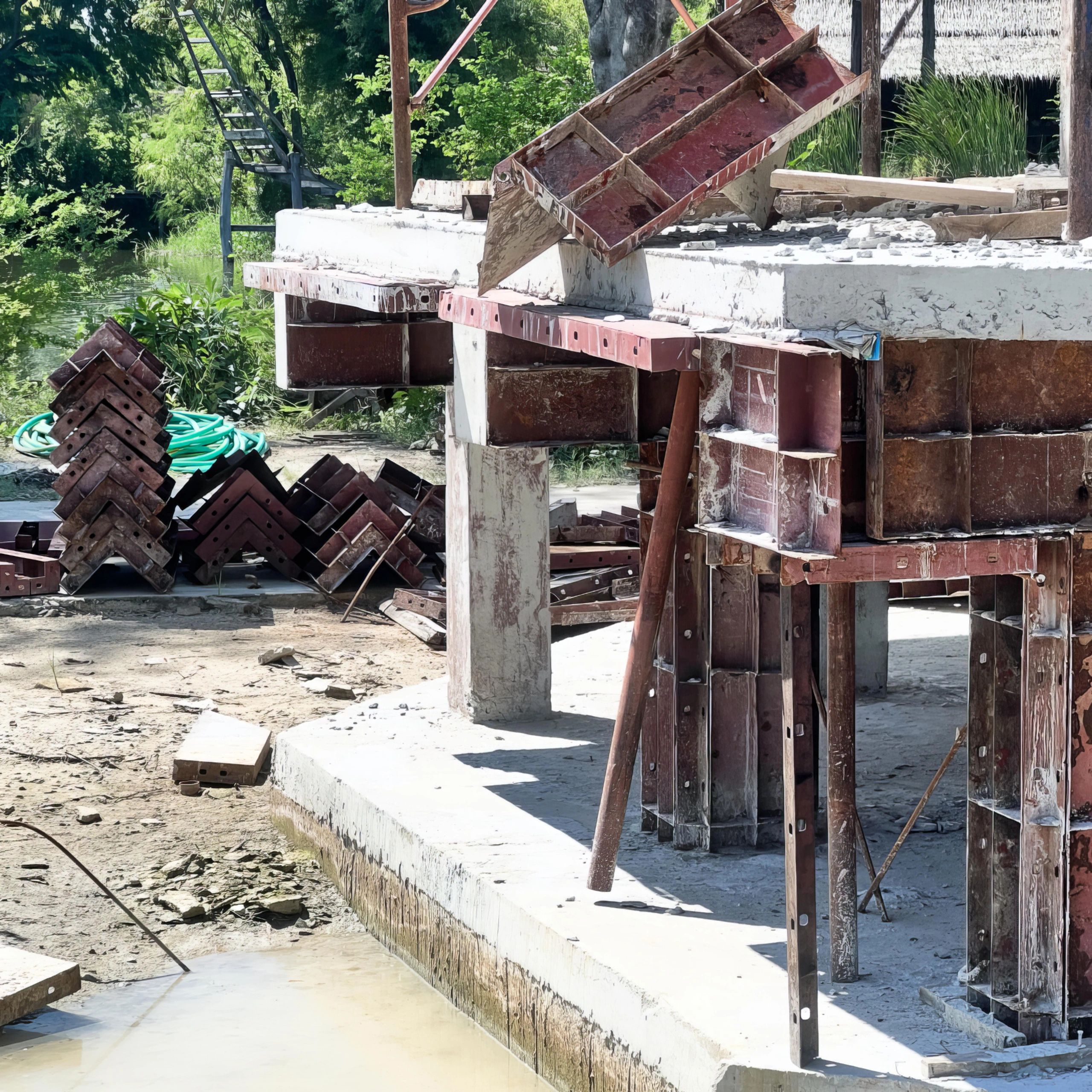 Concrete formwork and construction materials at a building site near water.