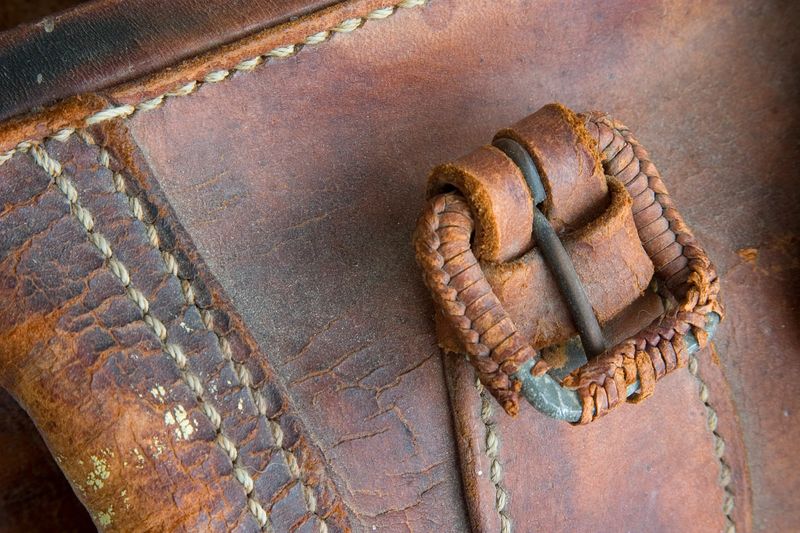 Closeup detail of the buckle and stitching on an antique leather travel handbag. Sharp. Processed RAW.
