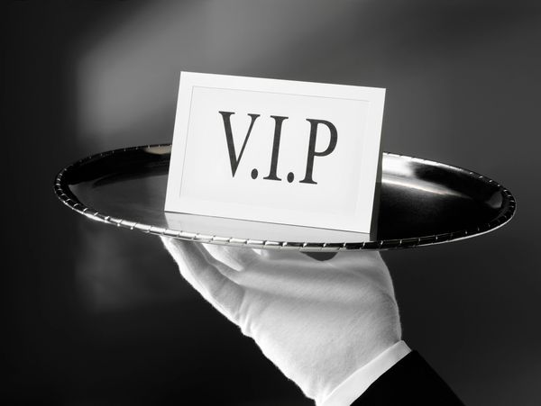 White-gloved hand holding a silver tray with a VIP card.