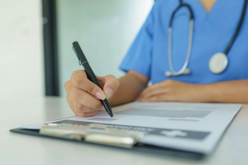 The doctor sitting at a desk and writing a prescription for her patient.