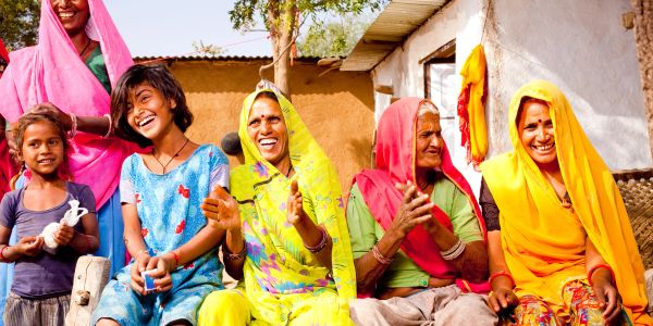 Group of smiling women and girls in colorful traditional attire.