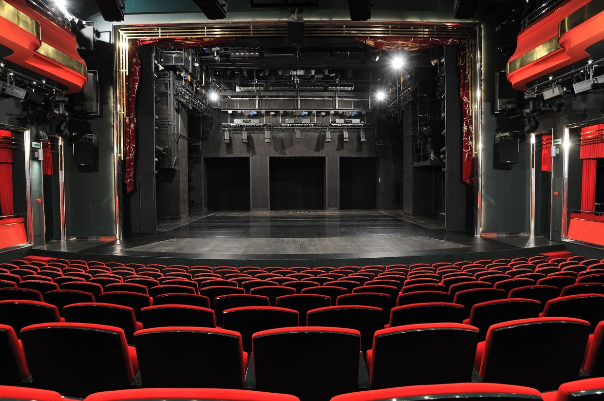Empty theater with red seats and stage.