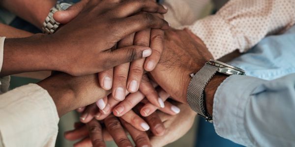 Multiple hands stacked together symbolizing unity.