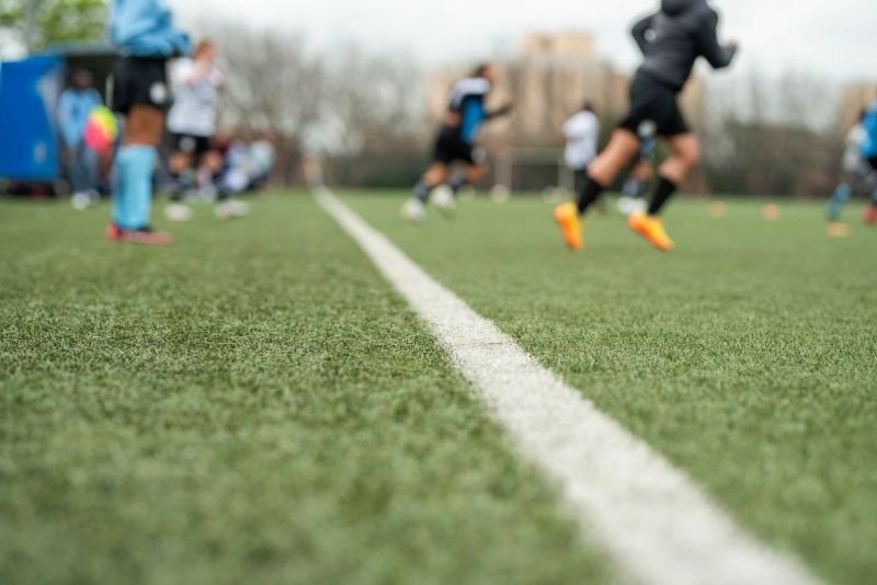 Young female soccer team running towards the sports field from the sideline during training session