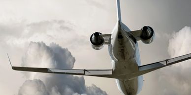 View from below of a jet airplane flying against a cloudy sky.