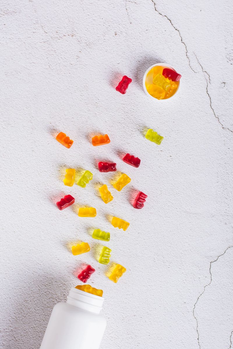 Bottle with gummy vitamin supplements in the shape of bears on the table top and vertical view