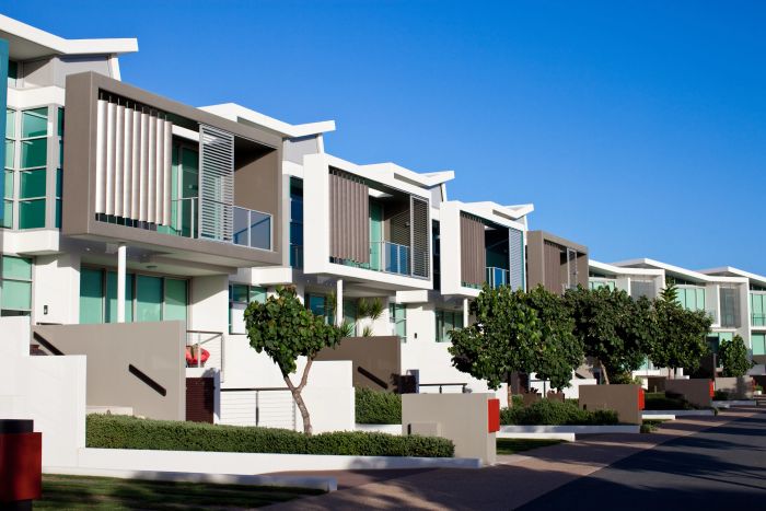 Modern white and gray townhouses under clear blue sky.