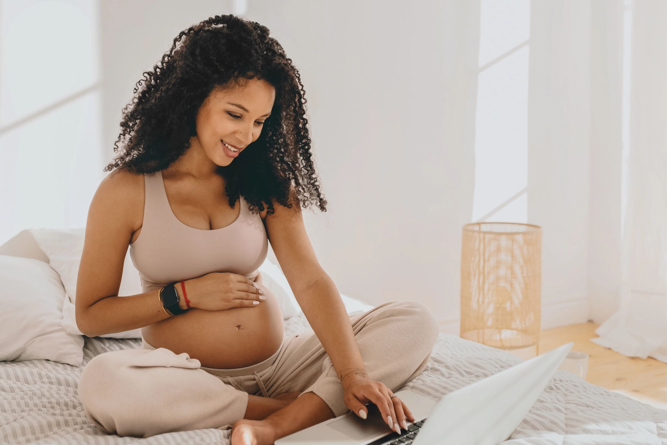 Pregnant woman using a laptop in a cozy room.