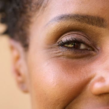 Image is a close-up of s young lady's eye. She appears to be smiling. Low vision support services in