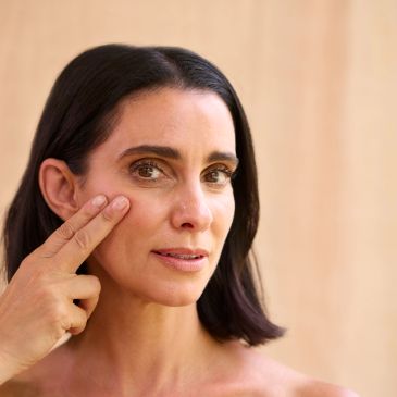 Woman touching her cheek with fingers.