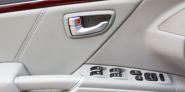 Close-up of a car door interior showing handle and control buttons.