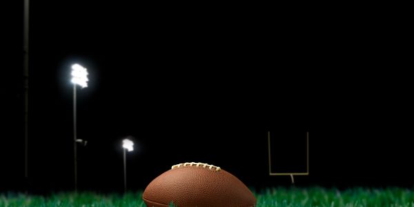 Football on the grass under stadium lights at night.