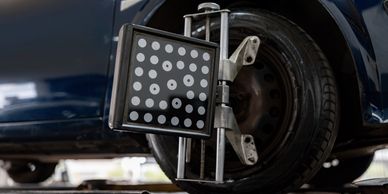Wheel alignment device attached to a car tire in a garage.