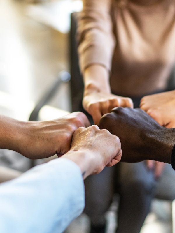 Diverse group of people joining fists in a team gesture.
