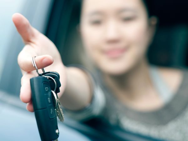 Person handing over car keys through an open car window.