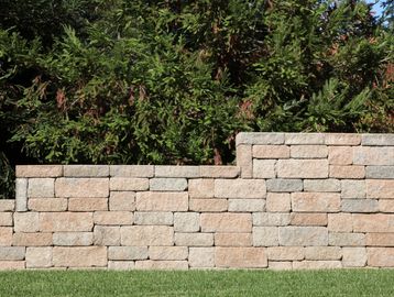 Stone retaining wall with greenery behind.