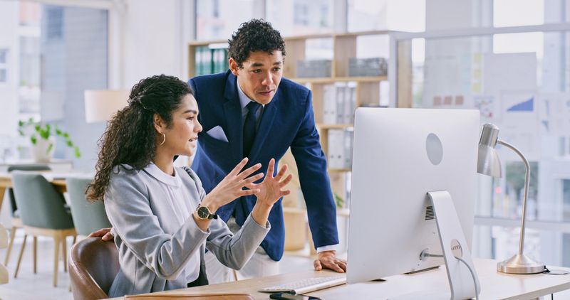 Computer, discussion and business people in the office for law project in collaboration. Conversation, technology and woman talk to man attorney manager for legal case on desktop in modern workplace.