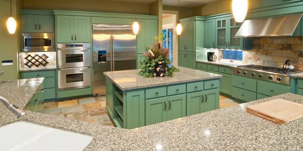 Cocina espaciosa con gabinetes verdes y encimeras de granito.