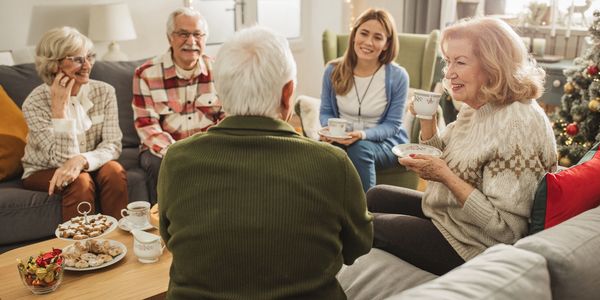 Seniors enjoying tea and snacks together in a cozy living room.