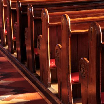 Rows of wooden church pews bathed in warm light.