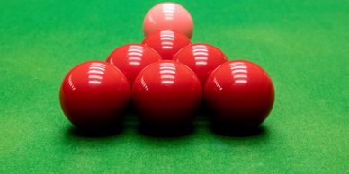 Six red snooker balls in a triangle formation.  Pink snooker ball above the six red snooker balls.