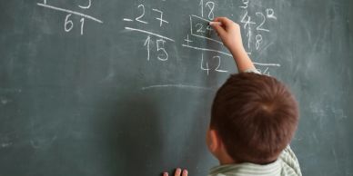A boy solving math problems on a chalkboard.