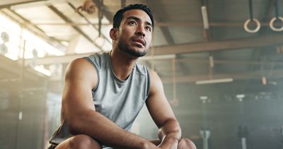 Athletic man resting and reflecting in a gym after workout.
