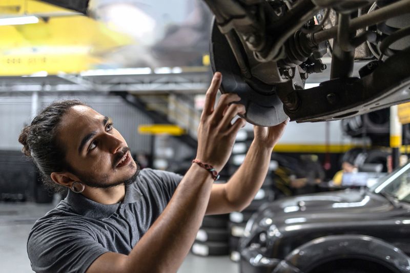 Latin man servicing a car brake disk in a mechanic's shop