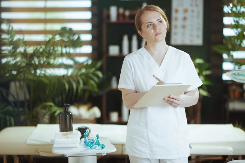 Healthcare time. female medical massage therapist in spa salon with clipboard.