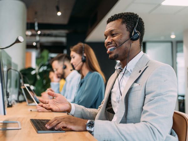 Customer service representatives working with headsets in an office.