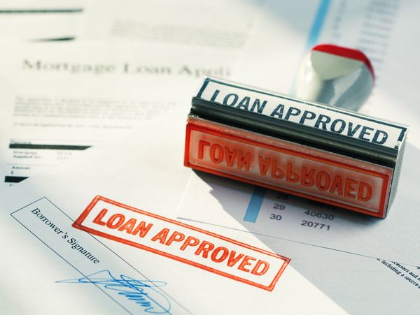 A red stamp marked 'LOAN APPROVED' on a signed mortgage loan application.