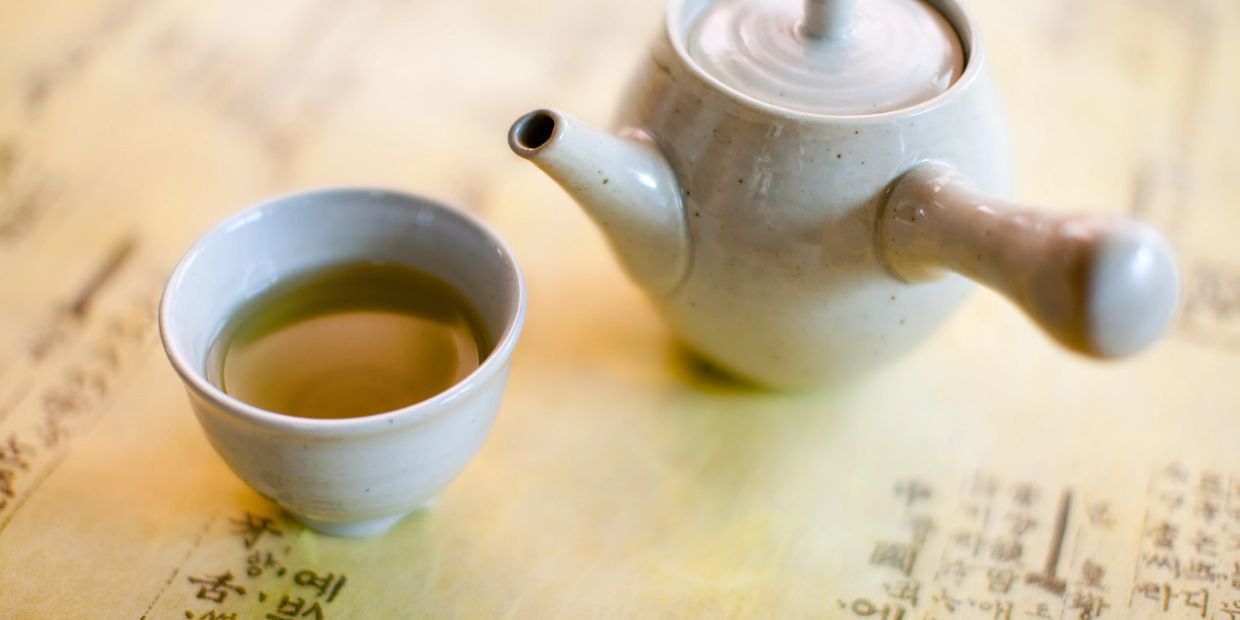 A cup and teapot on a table with text.