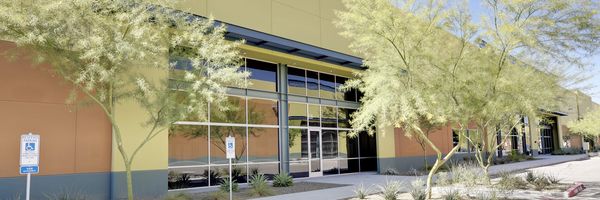 Modern commercial building exterior with desert landscaping and large windows.