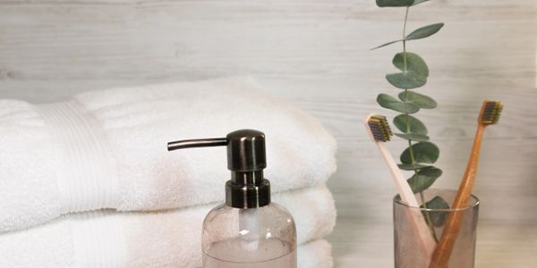 Bathroom essentials with towels, a soap dispenser, and toothbrushes in a minimalist setting.